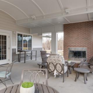 A cozy outdoor patio with comfortable seating and a brick fireplace.