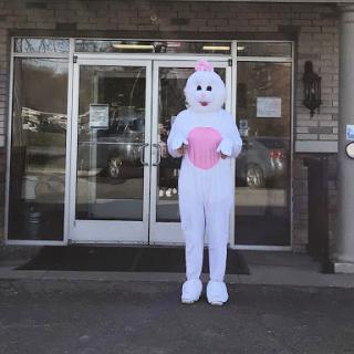 A person dressed in an Easter Bunny costume standing outside a building.