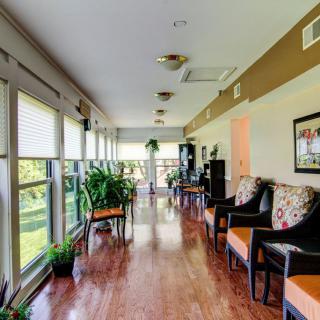 A bright hallway with large windows, greenery, and comfortable seating.