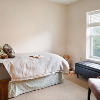 A cozy bedroom with a neatly made bed and a window letting in natural light.