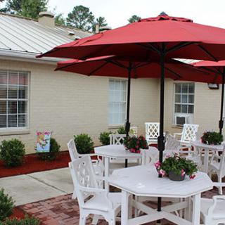 An inviting outdoor patio area with tables and chairs under red umbrellas.