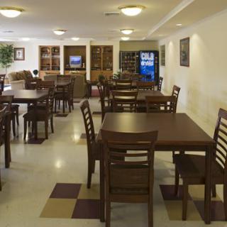 An empty dining area with tables and chairs, featuring a vending machine in the background.