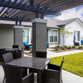 A patio with a pergola and outdoor furniture in a residential setting.