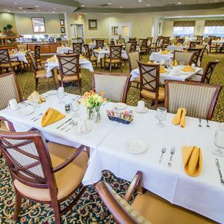 An elegant dining room with neatly set tables, featuring flowers and folded napkins.