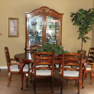 A classic dining room setup with a wooden table, matching chairs, and a display cabinet.