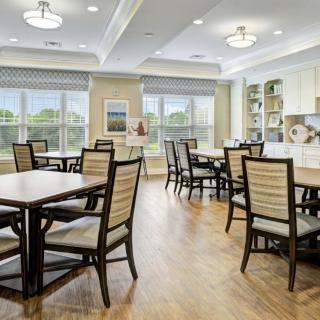 A bright and modern dining room with neatly arranged tables and chairs, featuring large windows and stylish lighting.
