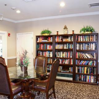 A cozy library with bookshelves, a table, and chairs arranged for reading.