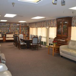 A spacious living room featuring a dining area, comfortable seating, and wooden furniture, illuminated by natural light.