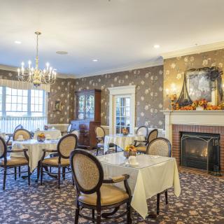 An elegant dining room with a chandelier, decorated with floral wallpaper and a fireplace.