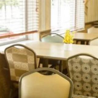 A cozy dining area with tables and chairs near large windows.