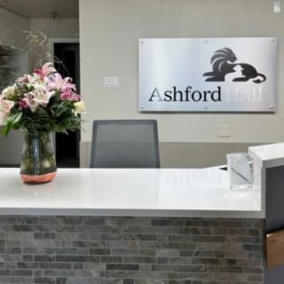 A reception desk with a flower arrangement and a sign reading 'Ashford' on the wall.
