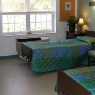 A bedroom with two twin beds, a large window, and a bedside lamp.
