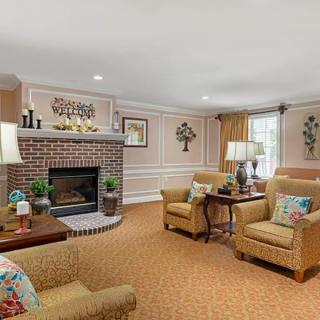 A cozy living room featuring a brick fireplace, comfortable seating, and traditional decor.
