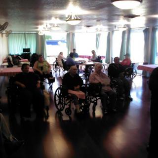 A gathering of elderly individuals in a community space, seated in wheelchairs and engaged in conversation.