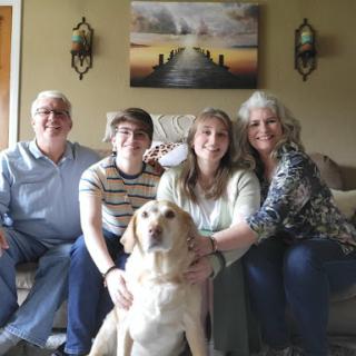 A happy family gathering with their dog.