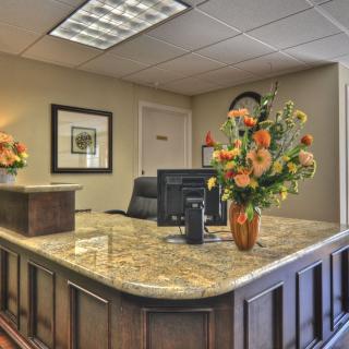 A well-organized office reception area with a granite desk and floral decorations.