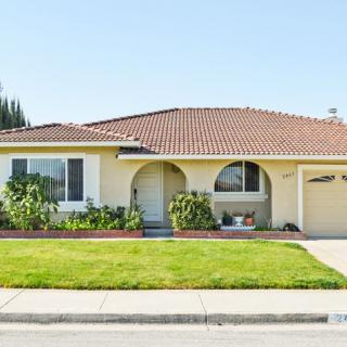 A suburban single-story house with a well-maintained lawn and garden.