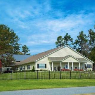 A well-maintained residential building set against a picturesque sky, surrounded by lush greenery.