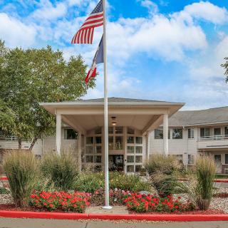 A well-maintained building entrance with flags and landscaped garden.