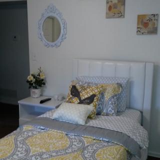 A cozy bedroom with a neatly made bed, decorative pillows, and a vase of flowers on the nightstand.