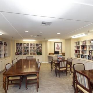 A cozy library with wooden tables and chairs, surrounded by bookshelves filled with books.