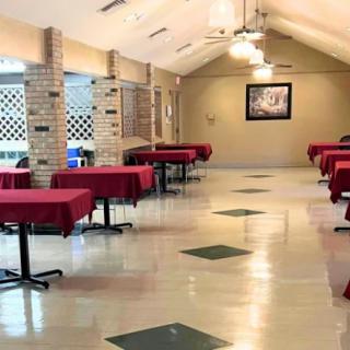 A spacious restaurant dining area with tables covered in red tablecloths.