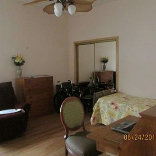 A bedroom with various furnishings, including a bed, chair, dresser, and mirror.