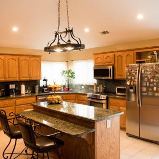 A modern kitchen with wooden cabinets, a granite island, and stainless steel appliances.