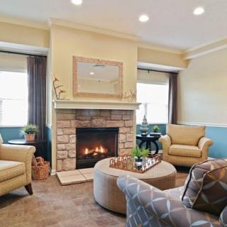 A cozy living room with a stone fireplace, armchairs, and warm decor.