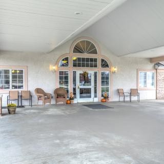A building entrance with a covered porch, featuring several chairs and decor.