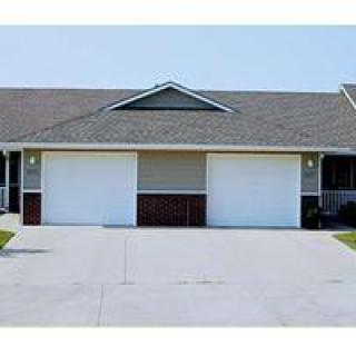 A suburban duplex with two garages and a wide driveway.