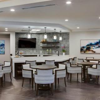 A modern lounge area featuring a bar counter, elegant seating, and stylish pendant lighting.