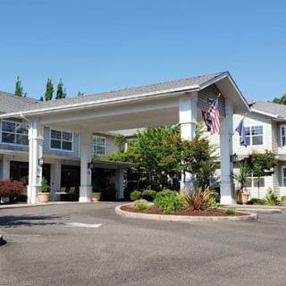 A large building with an entrance canopy and surrounding landscaping, featuring flags at the front.
