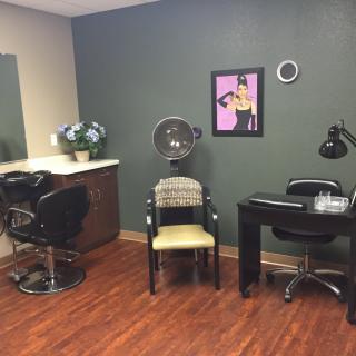 A cozy salon interior with a hair styling station and a nail table.