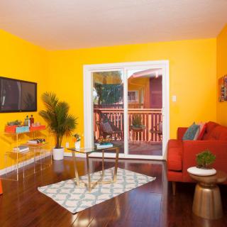 A vibrant living room with yellow walls, an orange couch, and modern decor.