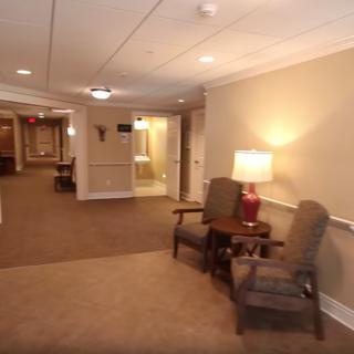 A well-lit hallway with comfortable chairs and a lamp.