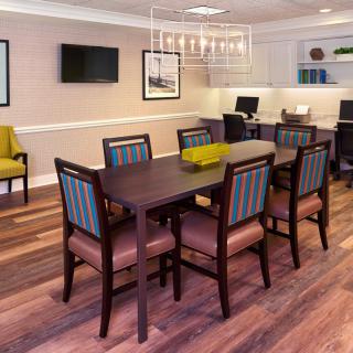 A modern dining room featuring a large table with chairs, elegant chandelier, and hardwood flooring.
