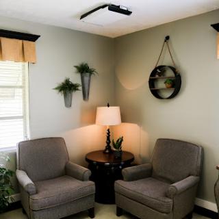 A cozy seating area in a living room featuring two comfortable chairs, a side table, and decorative plants.