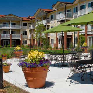 A modern apartment complex with outdoor seating and beautifully landscaped gardens.