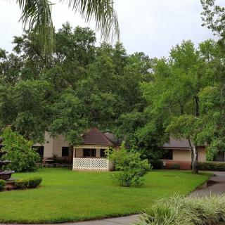 A scenic garden with a gazebo surrounded by lush trees and a well-maintained lawn.