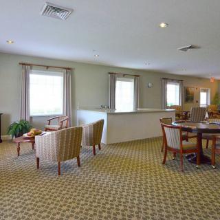 A spacious lounge area with comfortable chairs, tables, and a patterned carpet.