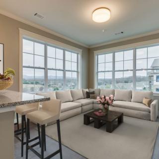 A modern living room with large windows and neutral-toned furniture.