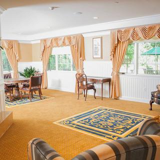 An elegantly furnished living room with large windows and warm-toned curtains.