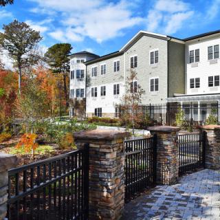 A residential building with a garden and fence surrounded by autumn trees.