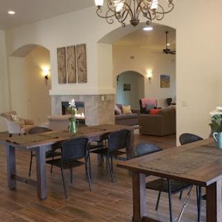 A spacious and inviting interior featuring a dining area with wooden tables and a cozy living space.