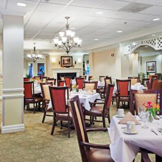 An elegant dining room with neatly arranged tables and chairs, featuring chandeliers and classic decor.