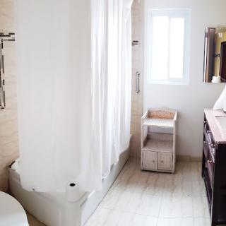 A bright and modern bathroom with a shower, sink, and natural lighting.