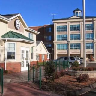 A commercial office building with multiple floors and a smaller adjacent structure on a clear day.