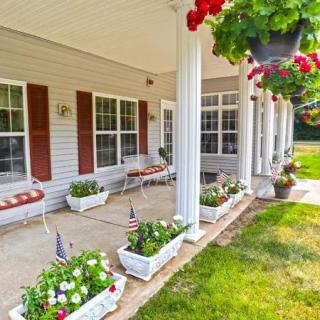 A charming porch with flower boxes and hanging plants, featuring white columns and seating areas.