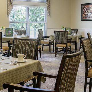 A restaurant dining room with neatly arranged tables and chairs near a large window.